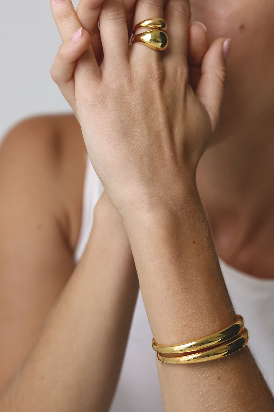 close up of woman's hands with focus on her chunky rings on her middle finger and 2 bracelet cuffs